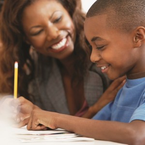 African American boy writing with female adult
