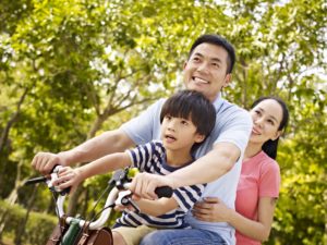 asian family riding bike in park