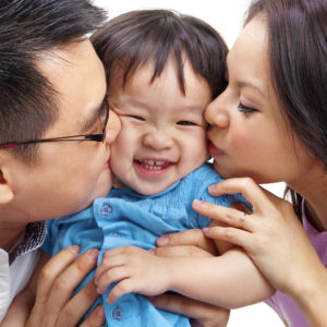 asian parents kissing baby